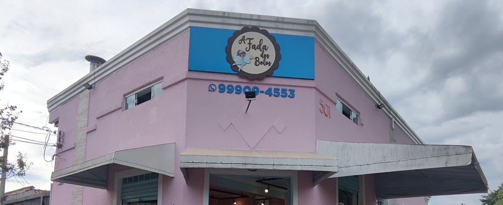 Fachada rosa da confeitaria, com a faixa azul e a logo