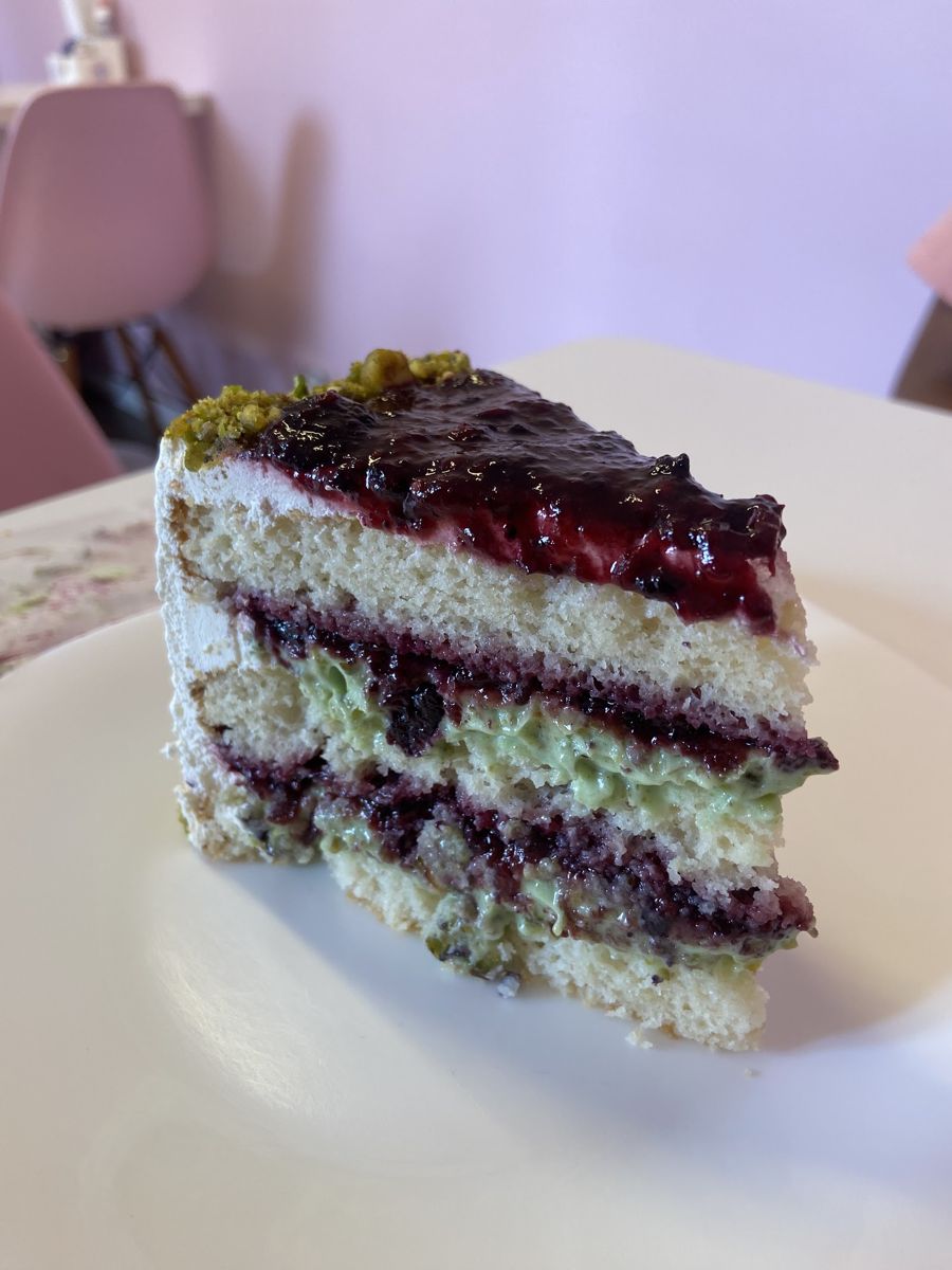 Fatia de bolo em camadas com geleia de frutas vermelhas e creme de pistache