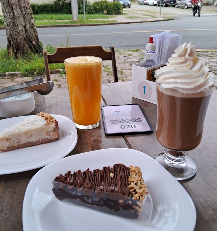 Mesa com suco, chocolate quente e fatias de bolo